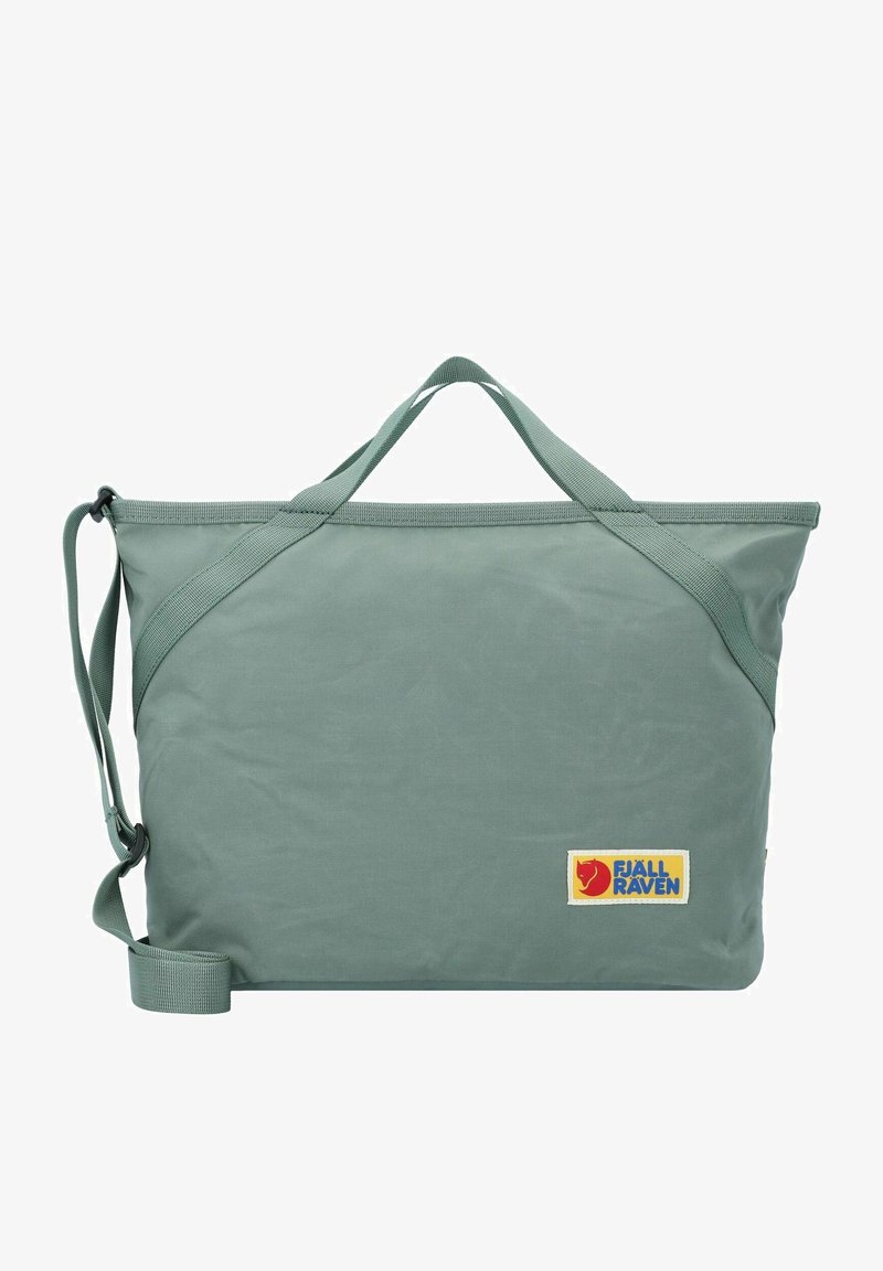 Zelená látková taška s dvojitými uchy a nastavitelným ramenním popruhem. Vybavena nášivkou s logem Fjällräven. Hladká textura a obdélníkový tvar.