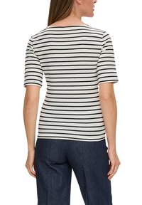 Gestreept t-shirt met korte mouwen. Witte stof met zwarte horizontale strepen. Klassieke ronde hals, zachte textuur, gecombineerd met donkere broeken.