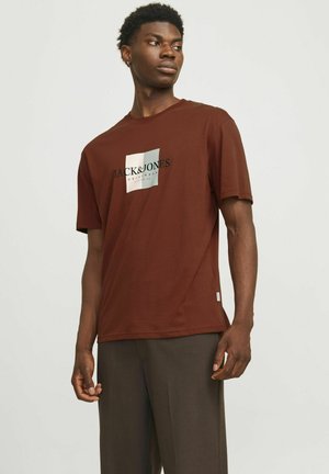 Brown short-sleeve t-shirt featuring a square graphic with "JACK&JONES" text in black and white. Smooth fabric with a relaxed fit.