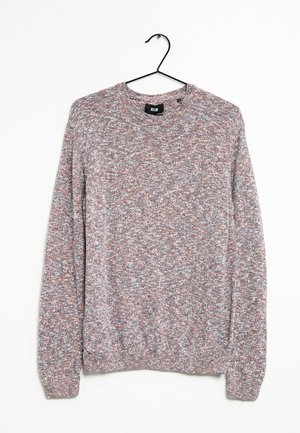 Pull en tricot à manches longues avec des fils mélangés gris, blanc et marron, suspendu à un cintre en métal noir sur un fond blanc.