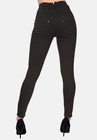 Jeans skinny neri a vita alta con schiena testurizzata, silhouette aderente e tasche. Abbinati a scarpe nere con tacco alto.