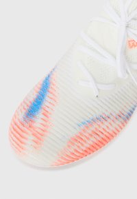 White athletic shoe with textured upper featuring pink and blue accents. Laces are white, and the sole has a rounded edge.