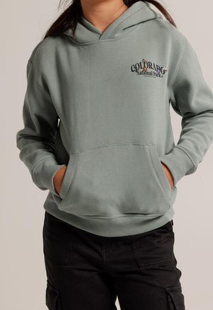 Jasnozielona bluza z kieszenią z przodu, kapturem ze sznurkiem i grafiką "Park Narodowy Kolorado". Wykonana z miękkiego, teksturowanego materiału.