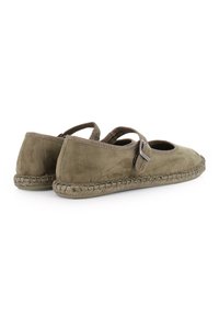 Zapatos de ante verde oliva con correa tipo Mary Jane, punta redondeada y suela de yute trenzado. Presentan un detalle de hebilla en la correa.