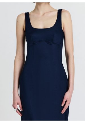 Dopasowana sukienka w kolorze granatowym, z szerokimi ramiączkami, kwadratowym dekoltem i profilowanymi szwami. Gładka tkanina z lekkim połyskiem. Bez widocznych ozdób.