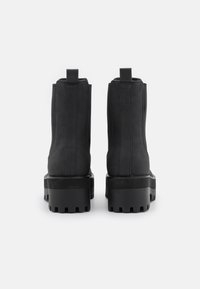 Black ankle boots featuring a smooth finish, elastic side panels, and a chunky tread sole. The design includes pull tabs on the back.