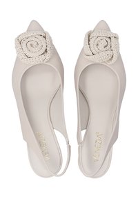 Špičaté slingback boty v světle béžové kůži, zdobené texturovanou krémovou růžovou aplikací na špičce, s hladkým povrchem.