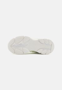 Lacoste sneaker talpa, fehér gumiból készült, texturált tapadással, ívelt formákkal és középső logóval rendelkezik. A felsőrész túlnyomórészt zöld színű.