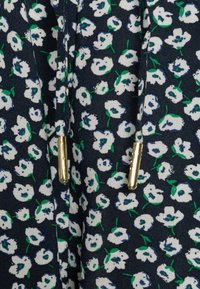 Tela de color navy con flores blancas y hojas verdes. Presenta detalles en dorado. Material texturizado y ligero con un patrón floral.