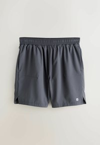Graue Sportshorts aus leichtem Stoff. Elastischer Bund, zwei Seitentaschen und Seitenschlitze für mehr Bewegungsfreiheit.