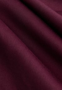 Burgunderstoff mit glatter Textur, der ein leicht glänzendes Finish und subtile Farbvariationen auf der Oberfläche aufweist.