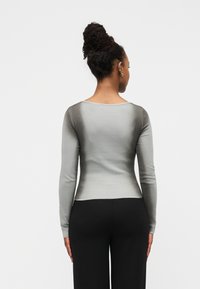 Μπλούζα μακρυμάνικη σε απαλό γκρι ύφασμα με βαθμιαία σκλήρυνση της απόχρωσης, με στρογγυλή λαιμόκοψη και εφαρμοστή γραμμή. Συνδυάζεται με μαύρο κάτω μέρος.