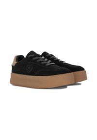 Sneaker in suede nero con suola piatta in gomma marrone chiaro. Presentano lacci grigi e un emblema a forma di stella sul lato. Texture morbida, design casual.