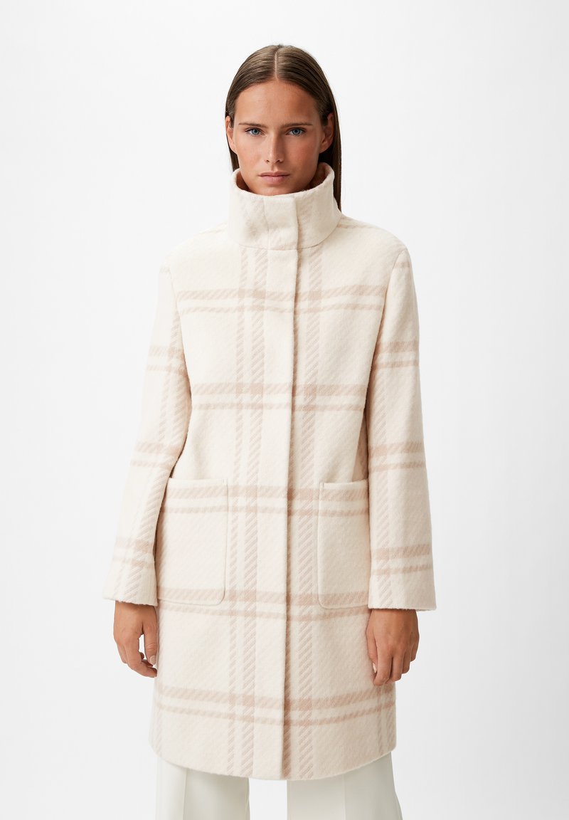 Cappotto a quadri crema con colletto alto, tasche laterali e una texture morbida con accenti rosa chiaro e una silhouette strutturata.