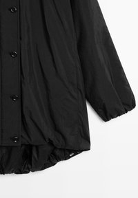 Giacca leggera nera con un tessuto liscio e strutturato, caratterizzata da una chiusura con bottoni, polsini elasticizzati e un orlo gathered nella parte inferiore.