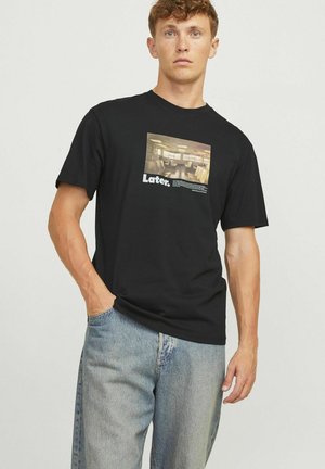 Black cotton t-shirt with a rectangular graphic print featuring a stylized hallway and the text "Later." in white. Casual fit, short sleeves.