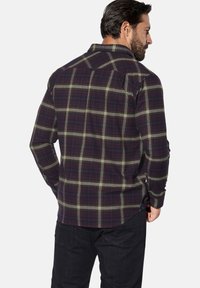 Herren-Karohemd in Dunkellila und Grün mit durchgeknöpftem Kragen, langen Ärmeln und abgerundetem Saum; weicher, strukturierter Stoff.