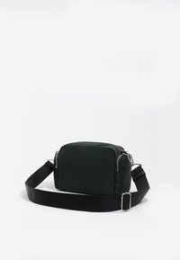 Bolso rectangular negro hecho de tela texturizada, con cierre de cremallera y correa ajustable, que presenta herrajes plateados y un diseño minimalista.
