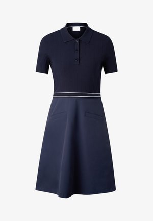 Tamnoplava haljina kratkih rukava s gornjim dijelom od rebrastog pletiva, polo ovratnikom, trima gumbima, bijelim dvostrukim prugama u struku i A-krojem suknje s džepovima.