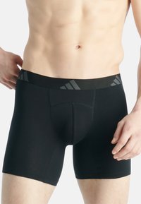 Zwarte boxershorts met een nauwsluitende pasvorm, elastische tailleband met grijze accenten en een gladde textuur. Ontworpen voor comfort en flexibiliteit.