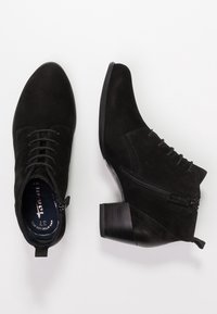 Botines de ante negros con un bajo tacón apilado, diseño de cordones y una cremallera lateral. Textura suave, puntera redondeada y lengüeta en la parte trasera.