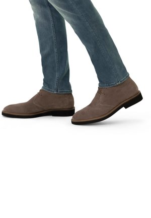 Grijze suede enkellaarsjes met een ronde neus en platte hak, met minimale stiksels en een vetersluiting. G gedragen met lichtblauwe jeans.
