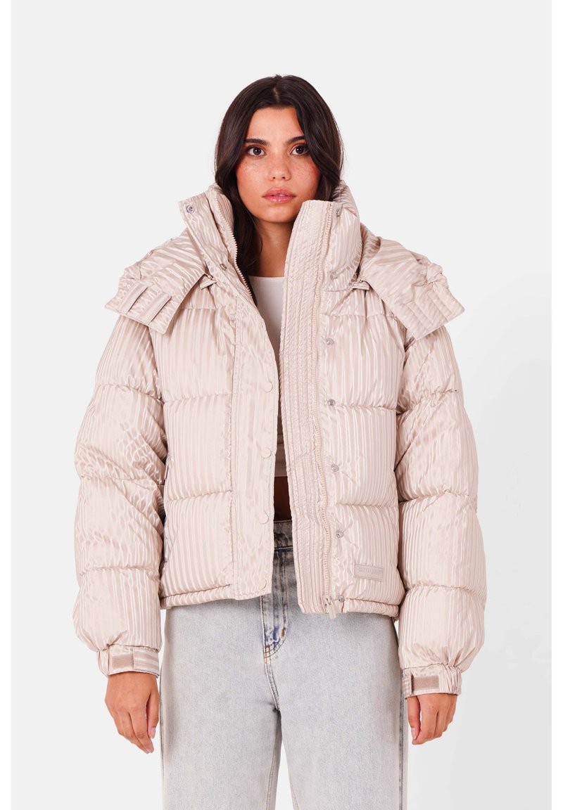 Polstret pufferjakke i lys beige med ribbet tekstur, oversized krave og trykknaplukninger. Har et cropped design og elastiske manchetter.