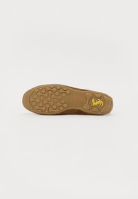 Brun semsket sneakersåle med en teksturert gummiklatt som har gult logo og sirkulære grep mønstre. Flat design, slitesterkt materiale.