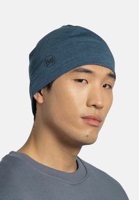 Light blue beanie made of a soft, stretchy material. Features a small black logo. Fitted design with a smooth texture.
