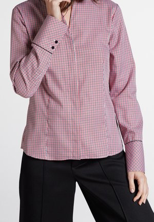 Camisa de cuadros roja y blanca con escote en V, mangas largas y botones negros en los puños. Textura suave, corte ajustado.