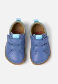 Blaue Lederschuhe mit zwei verstellbaren Klettverschlüssen, einem hellgrünen Absatzakzent und einer braunen Gummisohle. Innen mit einem hellbraunen Futter ausgestattet.