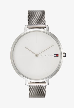 Minimalistisch zilverkleurig polshorloge met mesh band, witte wijzerplaat, zonder cijfers, slanke wijzers en Tommy Hilfiger-logo met vlag om 3 uur.