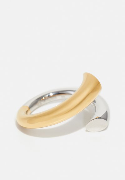 Brățară din metal cu un design elegant, curbat, în două nuanțe, cu partea din față aurie și partea din spate argintie, pe un fundal alb.