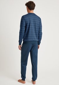 Donkerblauw pyjama set met een gestructureerd geometrisch patroon, bestaande uit een lange mouw top en een broek met elastische tailleband, van zacht materiaal en met aangesloten manchetten.