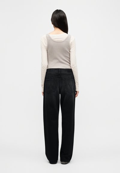 Γκρι ριμπ τοπ με τιράντες συνδυασμένο με μαύρο παντελόνι φαρδύ σε ψηλή μέση. Η πίσω όψη της στολής δείχνει δύο πίσω τσέπες και καθαρή μέση.