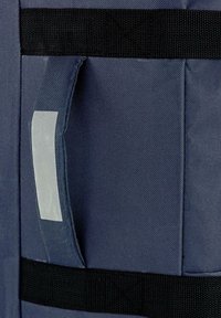 Mochila de tela azul marino con una superficie texturizada, con una asa gris y correas negras. El diseño incluye un parche rectangular.