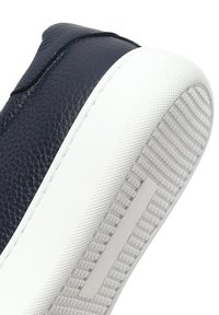 Granatowe skórzane sneakersy z teksturowaną cholewką, białą gumową podeszwą z wzorzystym bieżnikiem i minimalistycznym designem.
