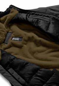 Interno di un giubbotto puffo nero con morbida fodera in fleece marrone, dotato di etichetta, e esterno in nylon nero con una texture liscia e bottoni.