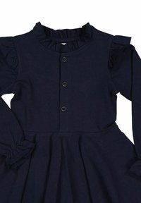 Laivastonsininen, pitkähihainen mekko, jossa on röyhelökaulus, napitettu etuosa ja liehuva helma. Valmistettu pehmeästä kankaasta, ja hihoissa on joustavat yksityiskohdat.