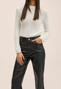 Suéter de punto gris claro con mangas largas, combinado con pantalones de imitación cuero negros de cintura alta que cuentan con detalles de costura y bolsillos laterales.
