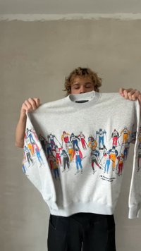 Γκρι φούτερ με πολύχρωμο γραφικό σκιέρ, που παρουσιάζει πολλαπλές φιγούρες με διάφορα ενδύματα. Καρμάνια και τελείωμα με ριμπ ύφασμα και στρογγυλή λαιμόκοψη.