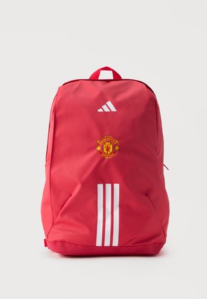Sac à dos rouge Adidas avec trois bandes blanches, logo de Manchester United sous l'emblème Adidas et poignée de transport supérieure.