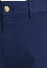 Marineblauwe broek gemaakt van lichtgewicht stof, met een vlak voorkant, knoopsluiting en een subtiele textuur met een gladde afwerking.