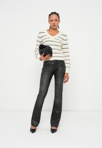 Pull en mélange de laine, crème avec des rayures noires ; jeans en denim gris évasés ; sac noir avec un détail de nœud ; escarpins noirs pointus.