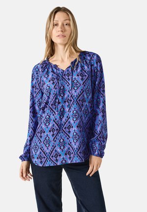 Langärmlige, gemusterte Bluse in Lila und Blau mit Diamantmustern. Verfügt über einen gerafften Ausschnitt und elastische Bündchen. Aus weichem Stoff.