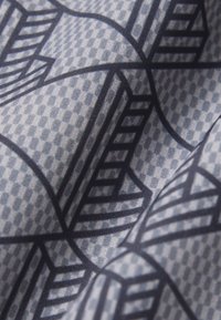 Tissu gris avec un motif de formes géométriques noires superposées et de lignes, créant un design abstrait en couches.