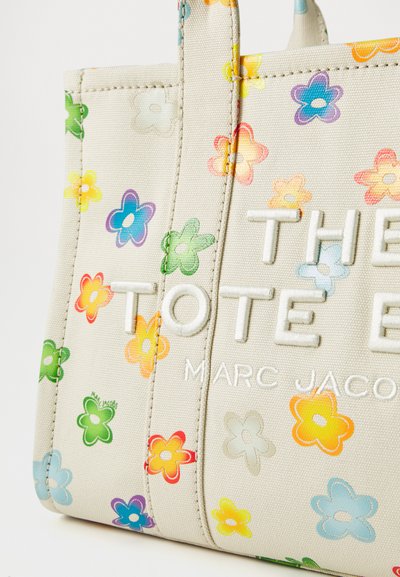 Beige tote bag med flerfargede blomstermønstre. Har brodert merkenavn, slitesterkt stoff og doble håndtak.