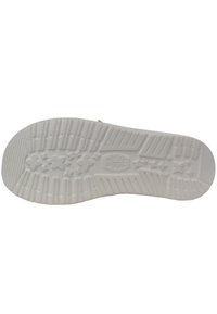 Witte rubberen zool met een gestructureerd loopvlakpatroon, met ster- en bloemontwerpen, en het 'HEY DUDE'-logo in het midden.