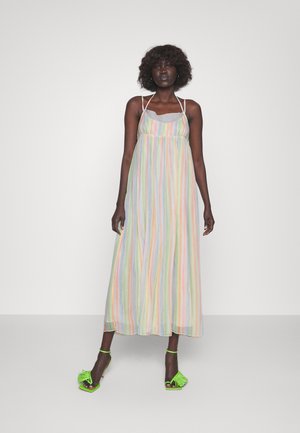 Robe maxi avec des rayures verticales pastel, en tissu léger, à bretelles spaghetti et avec un col à volants. Portée avec des sandales à talons vert vif.