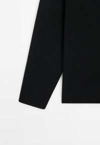 Czarny prążkowany sweter z długimi rękawami, o prostym kroju i teksturowanej tkaninie. Minimalistyczny design bez dodatkowych wzorów czy akcentów.